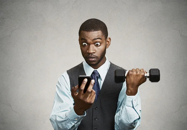 Corporate executive shocked by news on smart phone, lifting weig — Stock Photo, Image