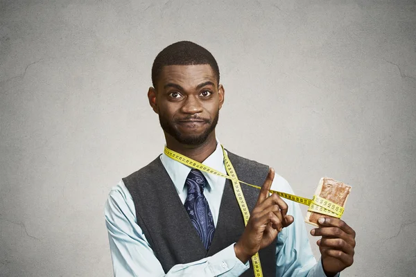 Hombre de aspecto gracioso tratando de no comer galleta dulce — Foto de Stock