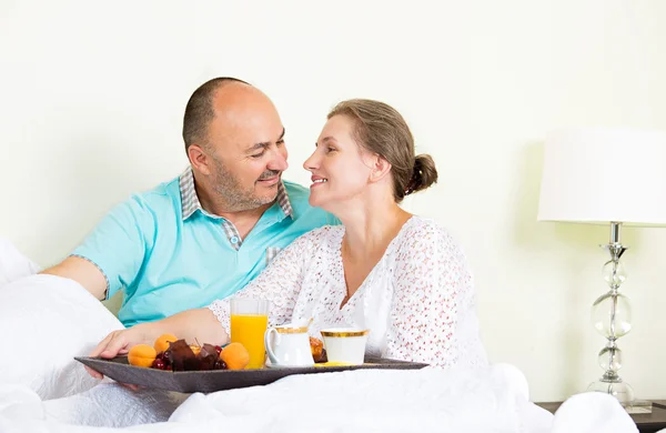 Pareja feliz disfrutando del desayuno, mañana en una cama — Foto de Stock