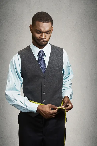 Unhappy businessman measuring his waist line. — Stock Photo, Image