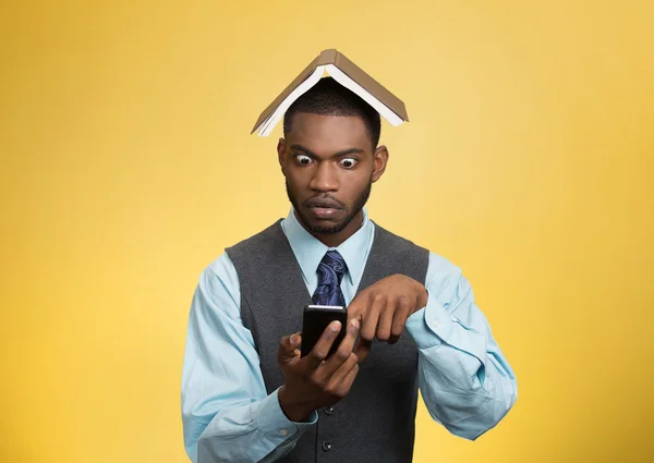Shocked man holding mobile, book over head — Stock Photo, Image