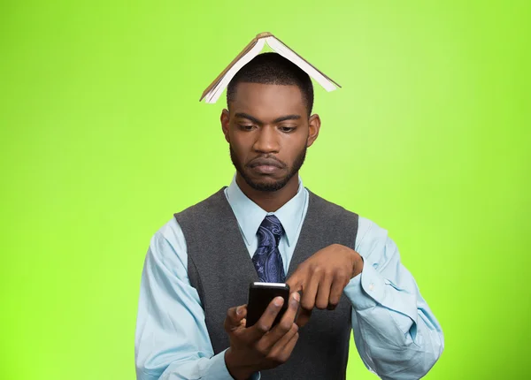 Man with book over head reading news on mobile — Stock Photo, Image