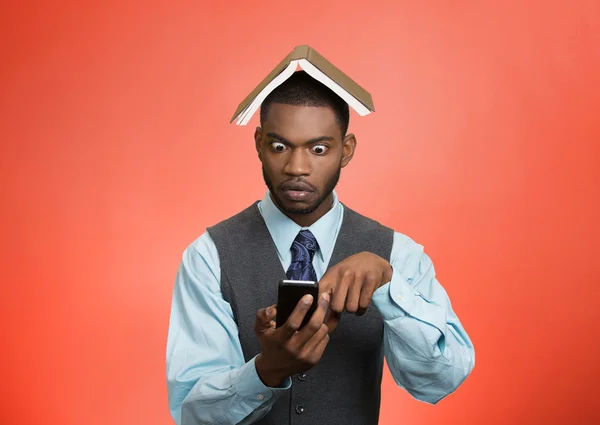 Hombre sorprendido sosteniendo móvil, libro sobre la cabeza — Foto de Stock