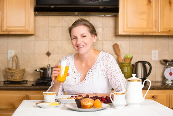 Middle aged woman having breakfast in a kitchen — Stock Photo, Image