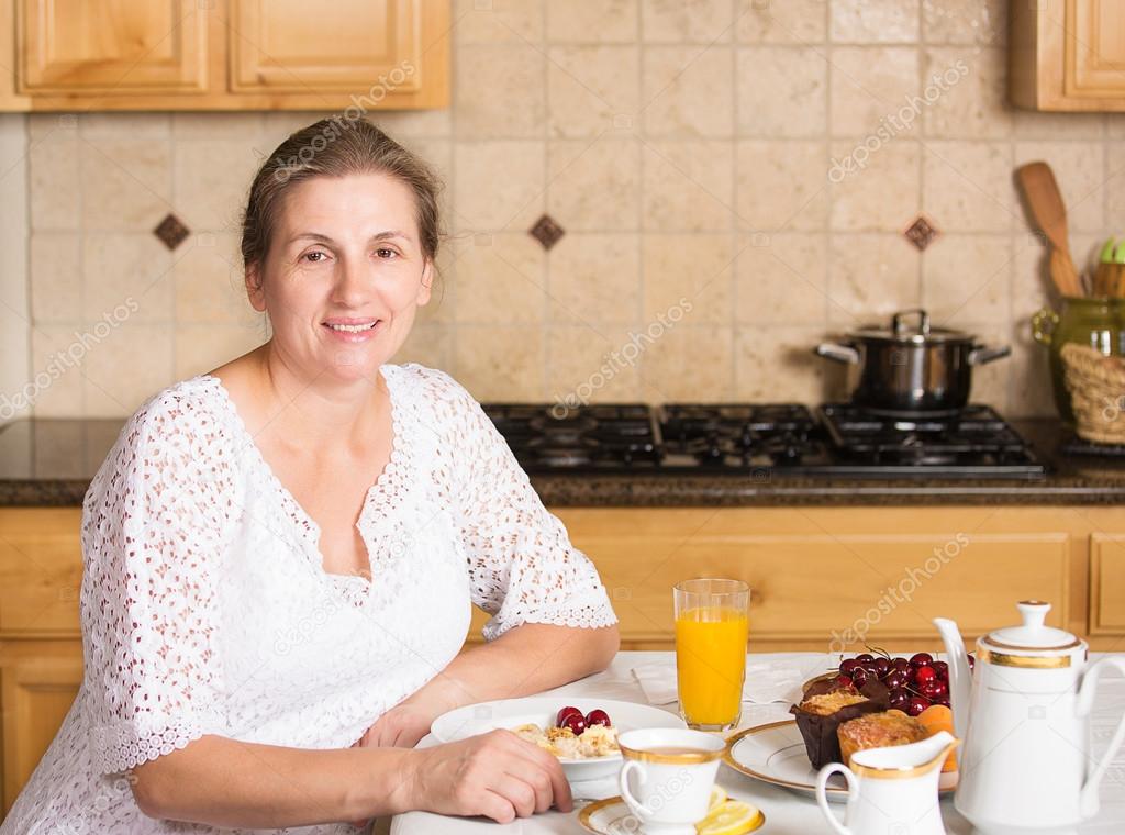 Middle aged woman having breakfast in a kitchen