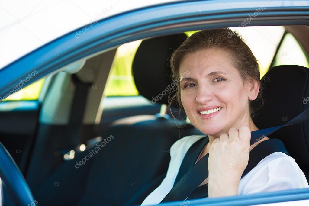 Woman pulling on seat belt inside her car