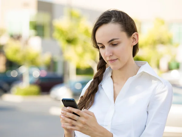 Serious young woman reading something on smart phone — Stock Photo, Image