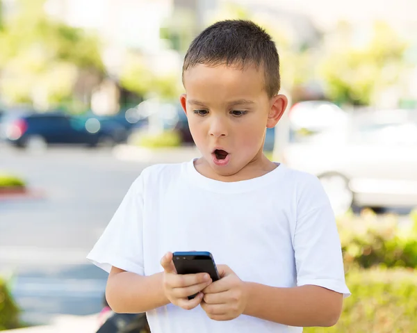 Förvånad pojke tittar på sin smartphone — Stockfoto