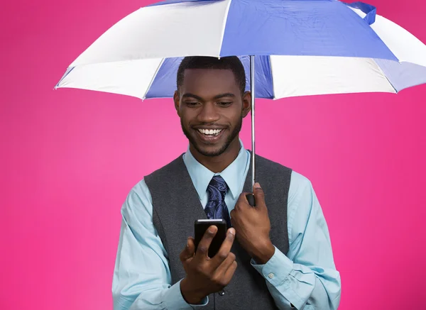 Glücklicher Mann, der unter einem Regenschirm SMS schreibt — Stockfoto