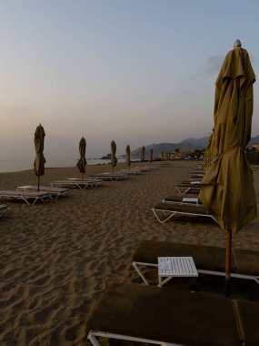 Sabahın erken saatlerinde plaj şemsiyelerinin henüz açılmadığı bir tatil beldesinde.