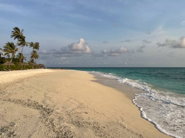 Dalgalar el değmemiş beyaz kumsala doğru koşuyor uzak bir tropik ada beldesinde Maldivler 'de.