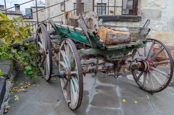 Yeşil kenarlı eski kırık ahşap vagon, üzerinde metal jantlar ve kütükler olan tekerlekler.