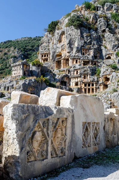 歴史的な石の劇場のマスクは ミラの古代のリュキアの都市でネクロポリスの岩カット墓の背景に円形劇場の浅浮き彫り 近代的なデムレ市 アンタルヤ県 トルコの領土 — ストック写真