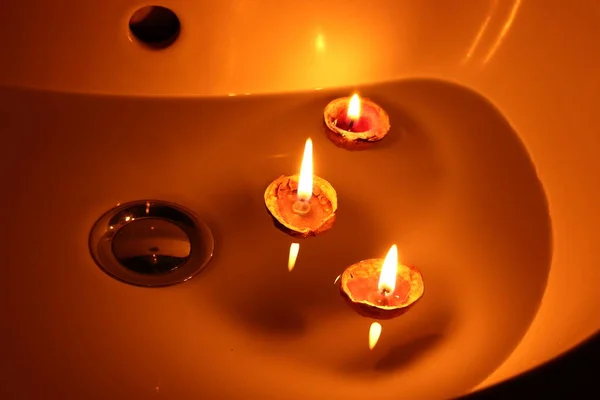 Три Свічки Плавають Поверхні Води Ванній Кімнаті Раковині Помаранчевий Фон — стокове фото