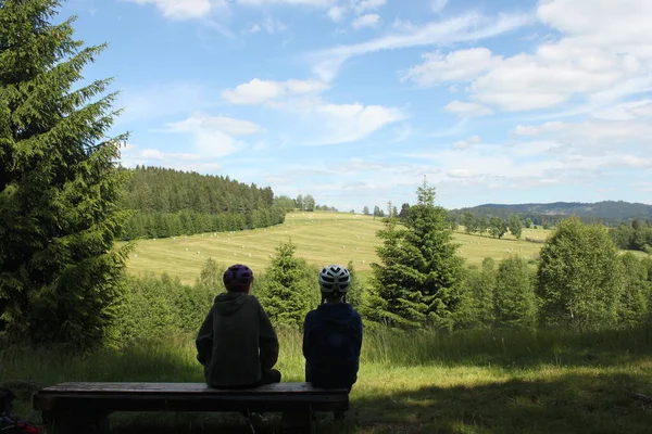 Silhouettes Two Child Cyclists Sitting Bench Front Mountain Panorama — стоковое фото