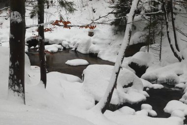 Güneş ve dereyle kaplı karlı dağ manzarası