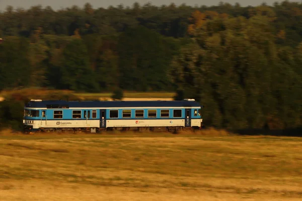 Panning Blue Train Passing Landscape Woods Field — Stock fotografie