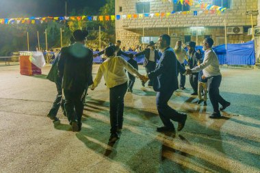 Güvenli, İsrail - 28 Eylül 2021: Simchat Torah geleneğinin bir parçası olan Musevi erkekler dans ediyor, kadınlar bariyerin arkasında, Safed (Tzfat), İsrail