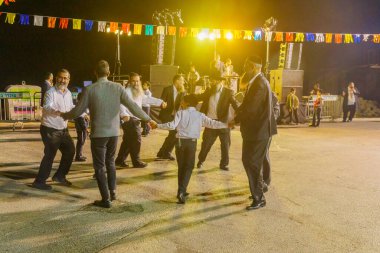 Safed, Israel - 28 Eylül 2021: Yahudi erkekler Safed (Tzfat), İsrail 'de Simchat Torah geleneğinin bir parçası olarak müzisyenlerin şarkılarıyla dans ediyor
