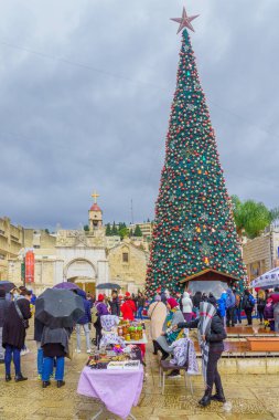 Nasıra, İsrail - 24 Aralık 2021: Nazareth, İsrail 'deki Yunan Ortodoks Annunciation Kilisesi, Noel ağacı, market tezgahları ve ziyaretçileri ile birlikte (Mary yakınlarında) kilise meydanı manzarası