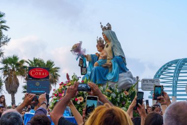 Haifa, Israel - May 01, 2022: Mary statue is photographed by believers, in Our Lady of Mount Carmel parade, near Stella Maris, in Haifa, Israel. This annual event commemorates its hiding in WWI