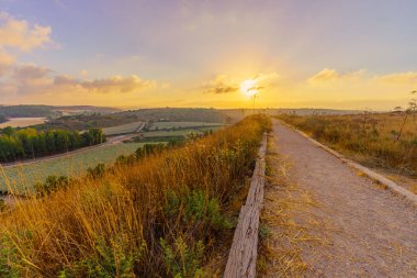 Sunrise view of a footpath, countryside and rolling hills, in Tel Lachish National Park, the Shephelah region, south-central Israel