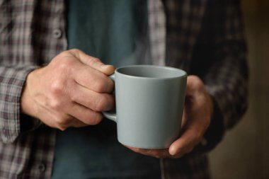 Bir adamın elinde bir fincan kahve.