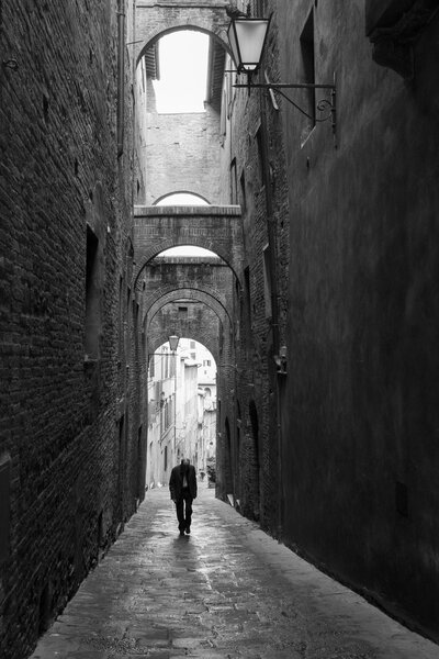 Lonely man walking down the alleys of Siena.
