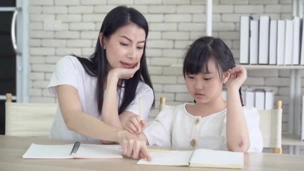 疲惫的年轻亚洲单身母亲头疼 教她的小女儿做作业 小女孩不懂家庭作业 她妈妈对此很不高兴 儿童教育问题 — 图库视频影像