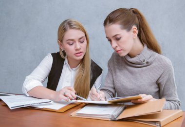 İş birliği sırasında konuşan iki genç iş kadını bir rapor ya da modern ofiste bir masada otururken evrak okuyorlar. Takım çalışması, iş toplantısı. Serbest çalışanlar.