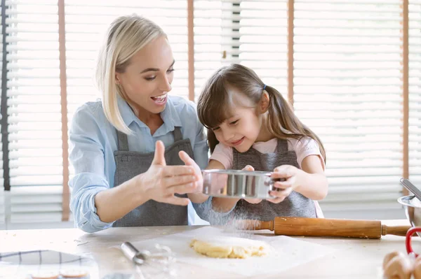 キッチンで家族料理を愛する幸せ 美しいお母さんと小さな娘が一緒に小麦粉で生地を振りかけるのを楽しんで 自宅で余暇を過ごし クッキーを焼く 一緒に家族の活動を楽しむ — ストック写真