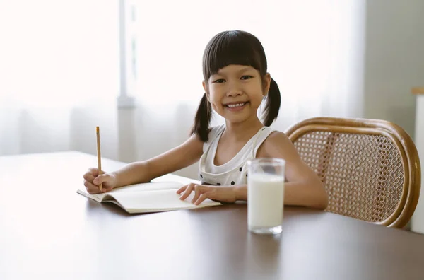 Smiling Asian Elementary School Girl Writing Drawingcoloring Pages Notebook Looking — Fotografia de Stock