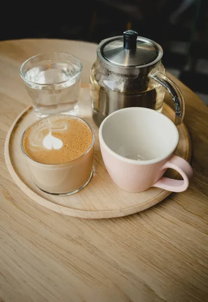 Holztablett Mit Getränken Cappuccino Leere Tasse Glasteekanne Wasser Gemütliche Kaffeestube — Stockfoto