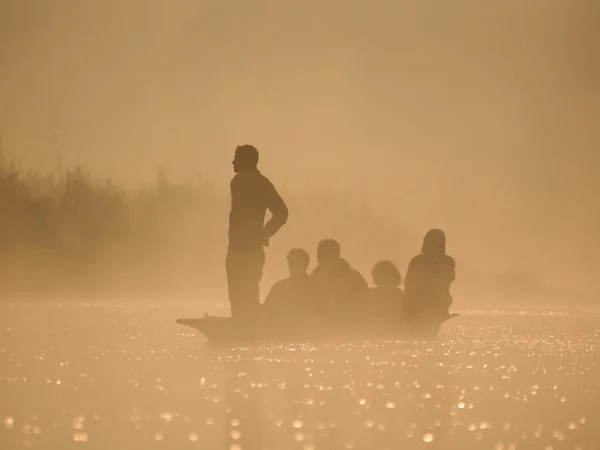 Mensen in kano bij dageraad op een mistige ochtend — Stockfoto