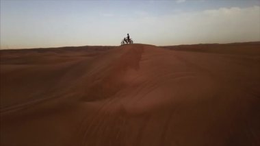 Bisikletli bir yarışçıyla Dubai çölünün hava aracı görüntüsü. Kumuldan geliyor. Rub al Khali, Abu Dabi, BAE. 4K, görüntüler.