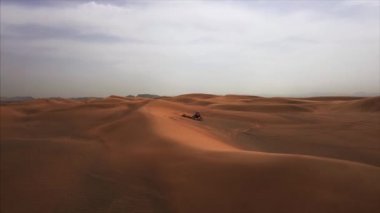Bisikletli iki yarışçıyla Dubai Çölü 'nün hava panoramik manzarası. Rub al Khali, Abu Dabi, BAE. 4K, görüntüler.