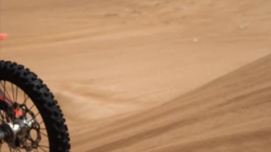 Yavaş çekimde motorsikletin kum tepeciğinde sürüşünü ve havada yüzüşünü yakından izle.