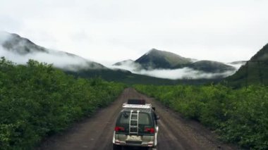 Kamçatka, Rusya-Aug 27,2020: Bulutların arasından dağlara çıkan bir yolda giden arabanın hava görüntüsü.
