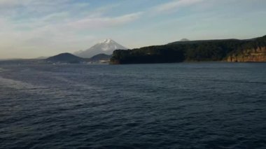 Deniz manzarası, orman ve ufukta büyük bir dağ. Kamçatka.