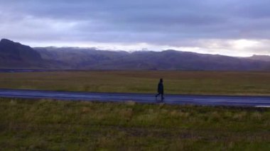 Çimen tarlalarında ve sıradağlarda yürüyen adamın hava manzarası.