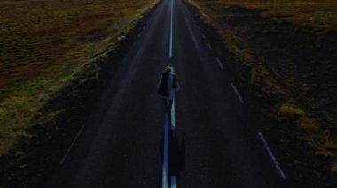 Man walking center of road into horizon, Iceland