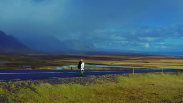 Panoramic view of man in white jacket walking on the road in steppe, Iceland — Vídeo de Stock