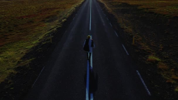 Man walking center of road into horizon, Iceland — Stockvideo