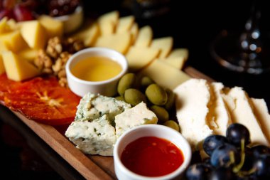 Siyah arka planda bir bardak şaraplı peynir tabağı.