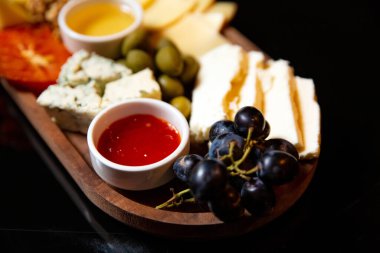 Siyah arka planda peynir tabağı. Yakın plan.