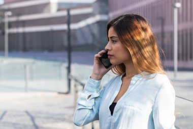 Çekici genç Latin kadın telefonda iş görüşmesi yapıyor. Kopyalama alanı ile iş kavramı