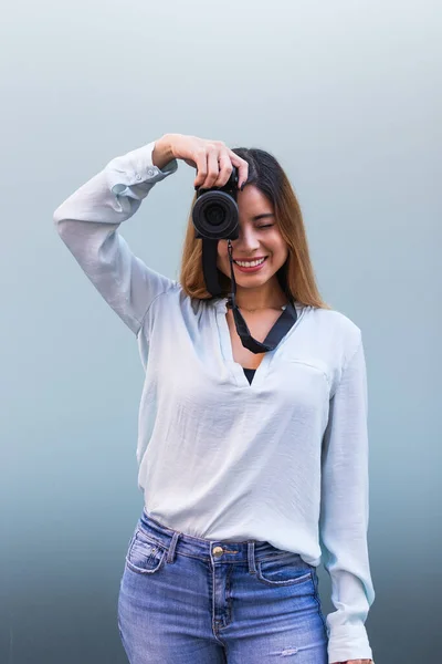 Profesyonel kamerayla fotoğraf çekerken gülümseyen fotoğrafçı portresi, güzel esmer kadın. Hobi konsepti
