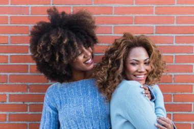Beyaz, kusursuz bir gülümsemesi olan Afrikalı doğal kızların güzel portresi. Gülümseyen Afro-Amerikan kadınları uzun afro saçlı, göz alıcı makyajlı ve mavi kazaklı. Dişçi konsepti