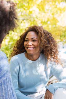 Mükemmel beyaz dişleri olan, arkadaşına gülümseyen Afrikalı Amerikalı bir kadın. Kıvırcık saçlı, mavi kazaklı, sohbet ederken gülümseyen Afro siyahi arkadaşlar. Dişçi konsepti