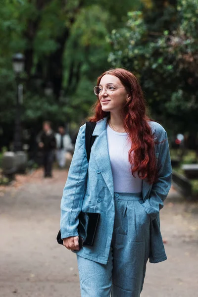 Mavi takım elbiseli çekici genç bir iş kadını elinde dijital tabletle parkta yürüyen profesyonel bir kadın mimar.